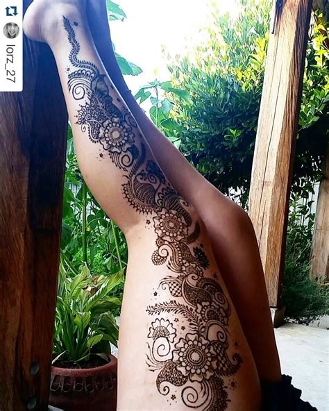 a woman s back with henna tattoos on her body and legs sitting in front of a potted plant