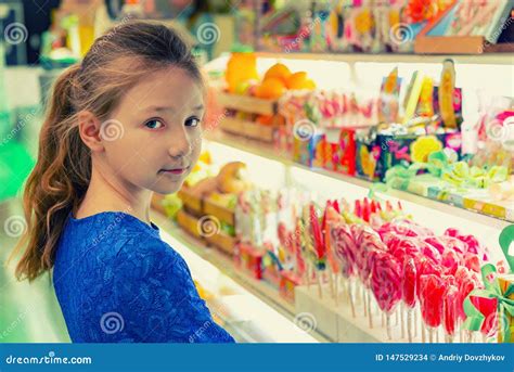 Uma Menina Em Uma Loja De Doces Escolhe Doces Coloridos E Pirulitos Foto De Stock Imagem De