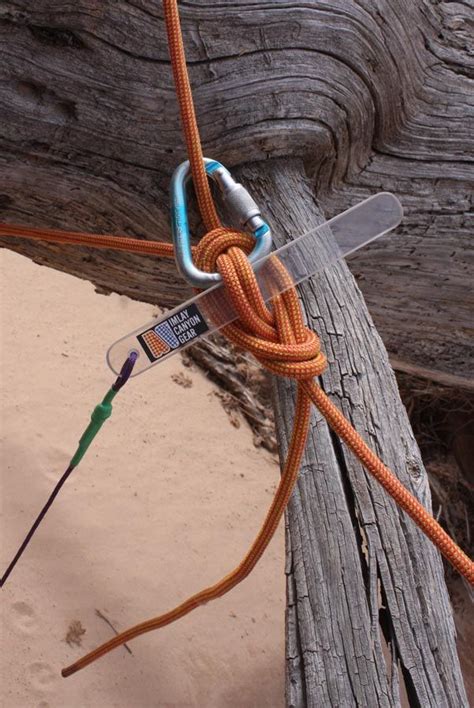 An Orange Rope Tied To A Wooden Post On The Beach With A Hook In It