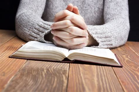 Woman Hands Praying With A Bible In Dark Over Wooden Table Stock Photo