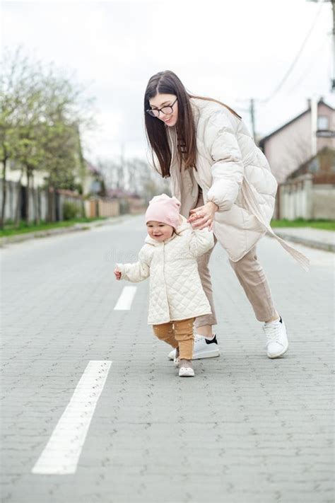 Little Baby Girl Learns To Walk With Mom S Help Outside Young Mother