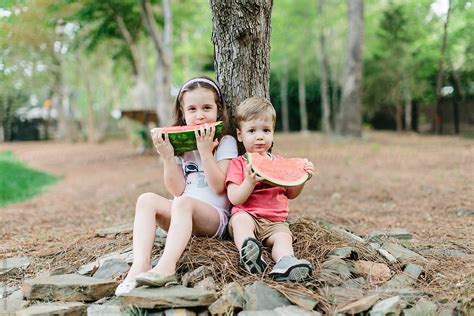 Cute Babe Babe And Girl Eating Watermelon Under A Tree By Stocksy Contributor Jakob