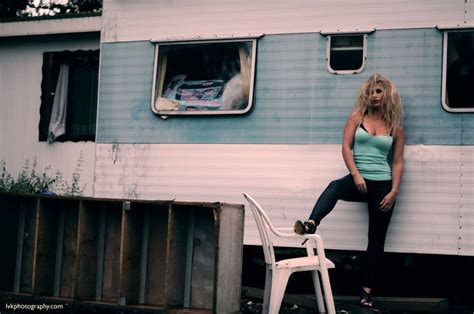 A Woman Sitting On Top Of A White Chair Next To A Blue And White Trailer