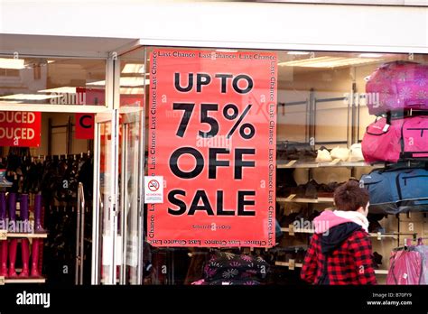 Up To 75 Off Sale Signs In Shop Window With One Female Shopper Passing