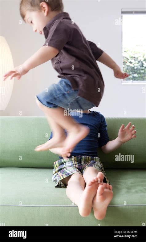 Junge Springt über Seinen Bruder Auf Sofa Stockfotografie Alamy