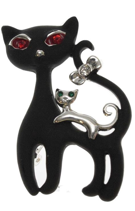 A Black Cat Brooch With Red Eyes Sitting On Top Of Its Back