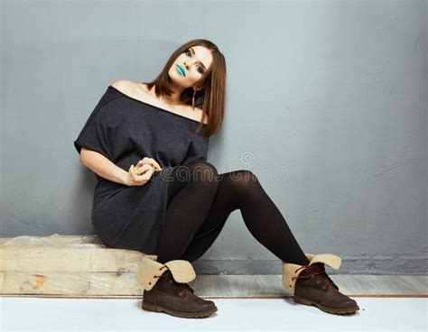 Portrait Of Fashion Full Body Model Seating Against Gray Wall Stock