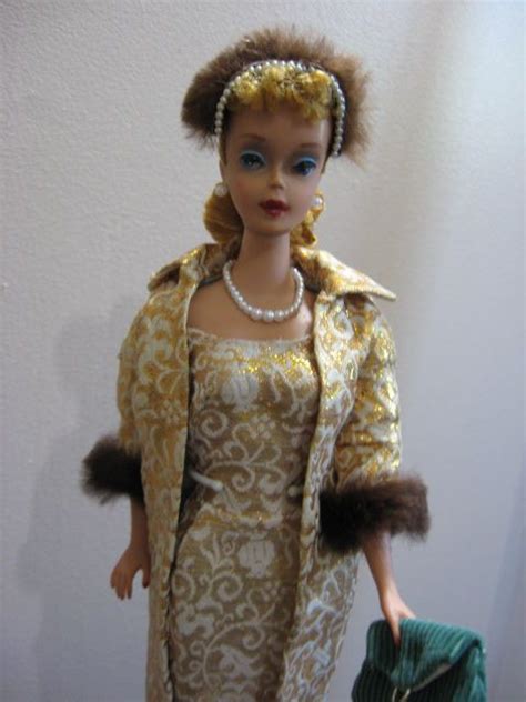 A Doll Dressed In An Elegant Dress And Fur Stoler Holding A Green Purse