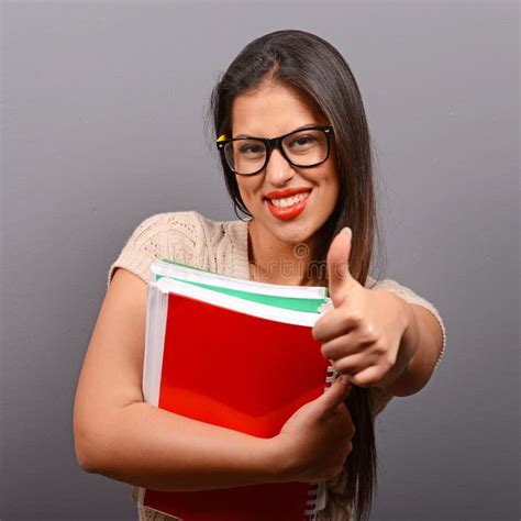 Portrait Of Happy Student Woman Holding Books With Thumb Up Against