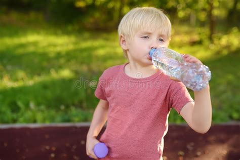 Little Boy Drinking Water During Workout With Dumbbells Stock Photo