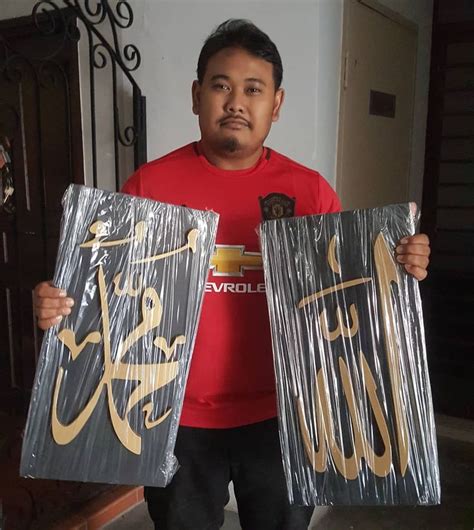 A Man Holding Up Two Bags With Gold Lettering On Them