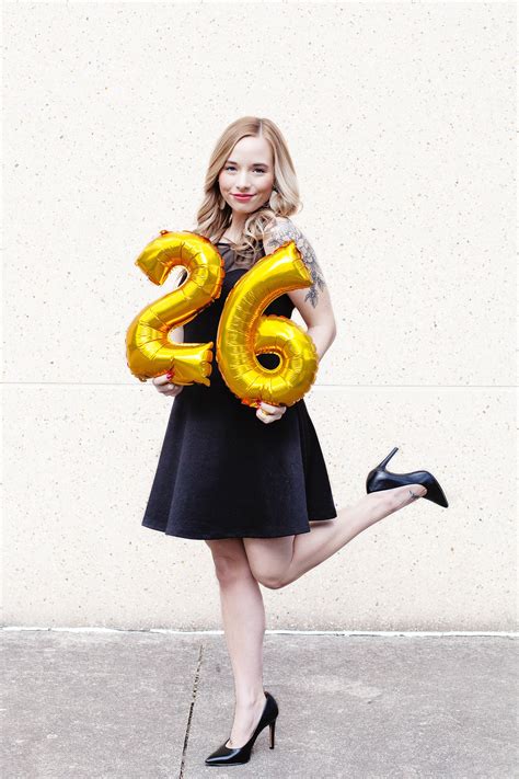 A Woman In Black Dress Holding Gold Balloons With The Number Twenty Six