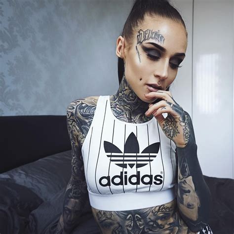 A Tattooed Woman Sitting On Top Of A Bed