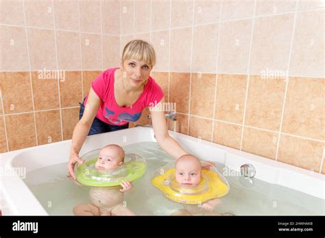Newborn Twins Swimming In The Bath Or Bathtub Mother Help Them Swim