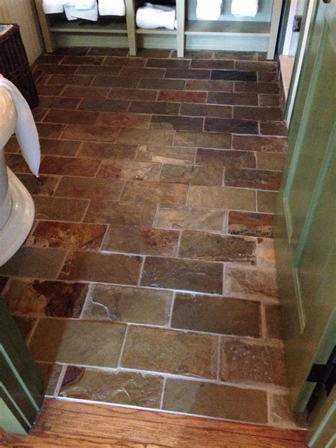 A Bathroom With Stone Flooring And Green Cabinets