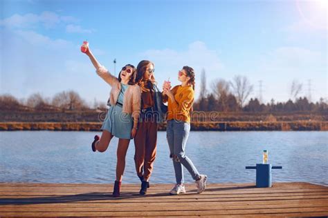 Shoot Of Three Beautiful Girls Outdoors By The River Female Friends Relaxing By The River And