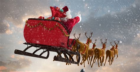 Santa Claus Flying With Reindeer Sleigh And Big T Box On Chimney At