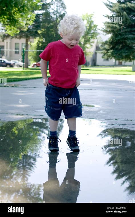 Toddler Boy Splashes In Puddle On Town Playground Stock Photo Alamy