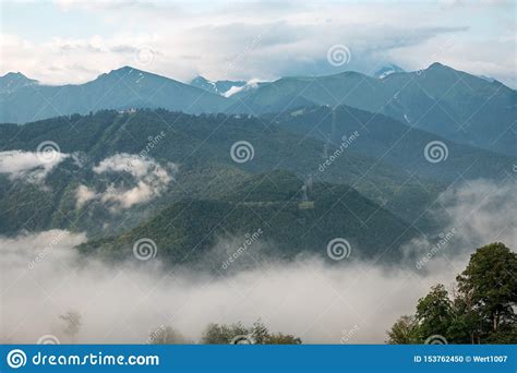 Clouds And Fog On The Slopes Of Mountain Ranges With Snowy Peaks In
