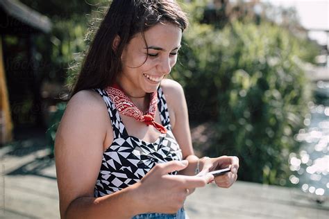A Portrait Of A Woman Using Her Phone With A Wide Smile On Her Face By Stocksy Contributor
