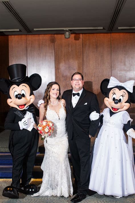 A Bride And Groom Pose With Mickey Mouses In Front Of The Stage At