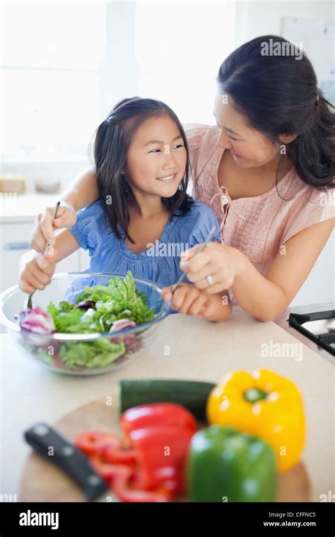 Una madre mira a su hija como sonríen y lance una ensalada Fotografía de stock Alamy