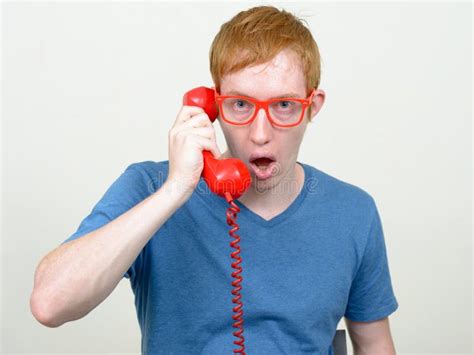 Man With Red Hair Talking On Old Telephone And Looking Shocked Stock