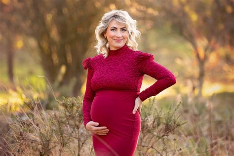 Beautiful Blond Pregnant Woman In A Stunning Red Gown Posing For A Maternity Portrait On A Sunny