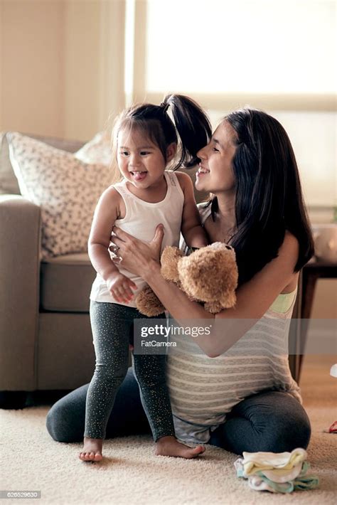 Young Pregnant Mother Holding And Laughing With Her Young Daughter