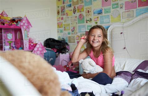 Smiling Girl Sitting On Bed And Brushing Hair In Bedroom Stock Photo Dissolve