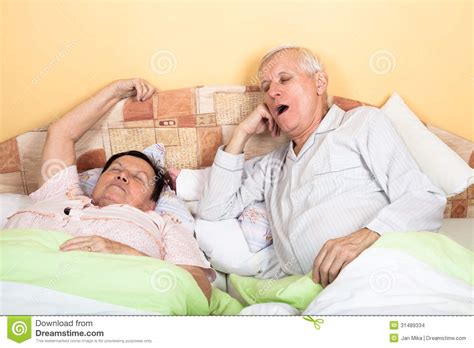 The couple is feeling romantic. Sleepy Senior Couple Yawning In Bed Stock Images - Image ...