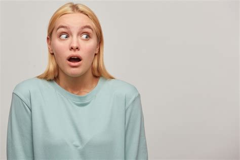 Free Photo Worried Scared Blonde Woman Looks Aside Around With Mouth Opened Frightened Afraid