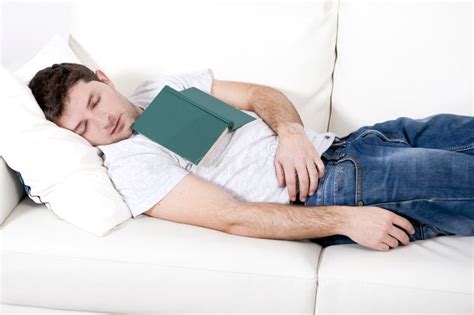 Tired Young Man Sleeping On Couch With Book On Lap Stock Photo Image