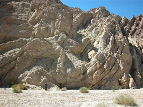 A Person Standing In The Middle Of A Desert With Large Rocks On It S Sides