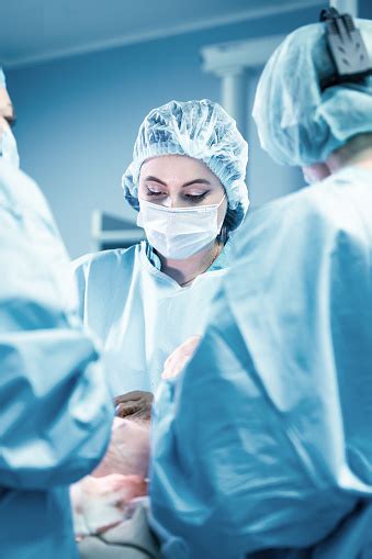 Female Surgeon With Operating Assistants Surgeons During Work Blue