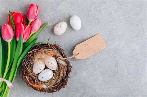 Easter Eggs In The Nest With Pink Tulips Bouquet On Gray Stone