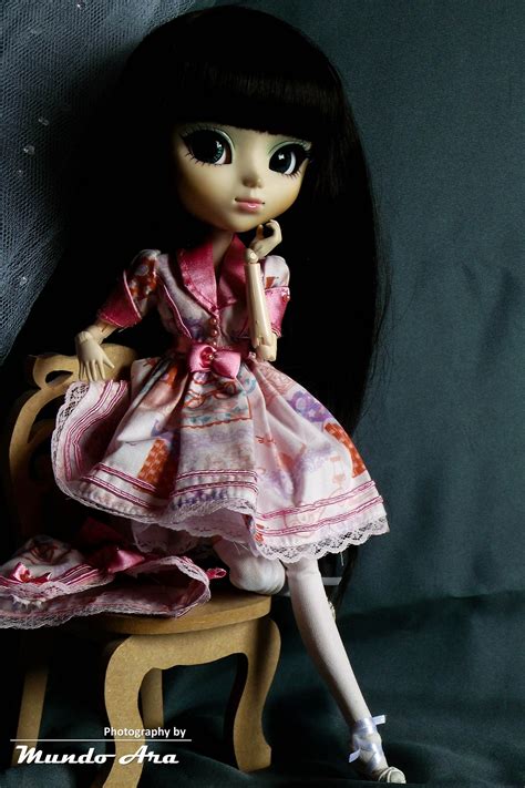 A Doll Sitting On Top Of A Wooden Chair Next To A Black Wall And