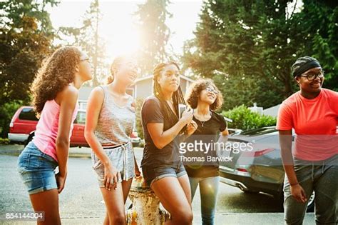 Smiling Teenage Girls Hanging Out In Neighborhood On Summer Evening