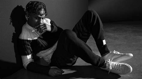 Black And White Photo Of Travis Scott Is Looking Down Wearing Black And