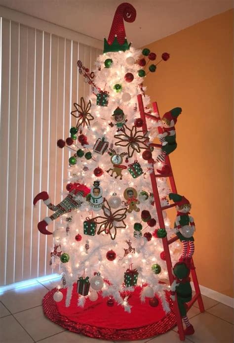 A White Christmas Tree With Lights And Decorations On It In Front Of A Window Next To A Red Ladder