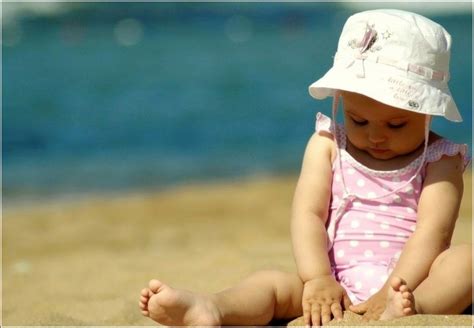 Фото Маленькая девочка в панамке сидит на пляже