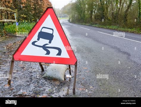 Slippery Road Triangular Warning Sign On A Flooded Road In The Uk Stock