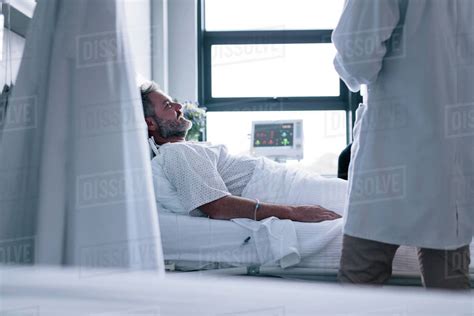 Sick Man Lying In Hospital Bed With Doctor Male Patient Getting