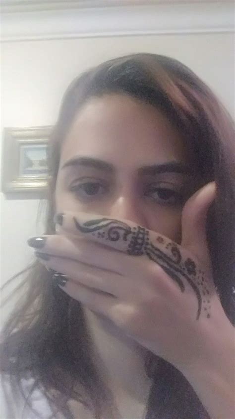 A Woman Holding Her Face Covered With Henna On Top Of Her Hand And Looking At The Camera