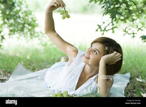 Young Woman Lying On Grass Holding Up Grapes Stock Photo Alamy