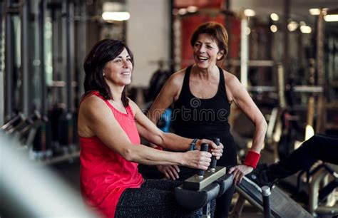 Two Cheerful Senior Women In Gym Doing Strength Workout Exercise Stock