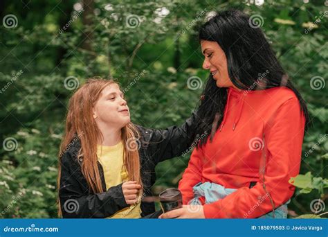 Happy Mother And Her Cute Daughter Sitting In Forest And Talking Stock