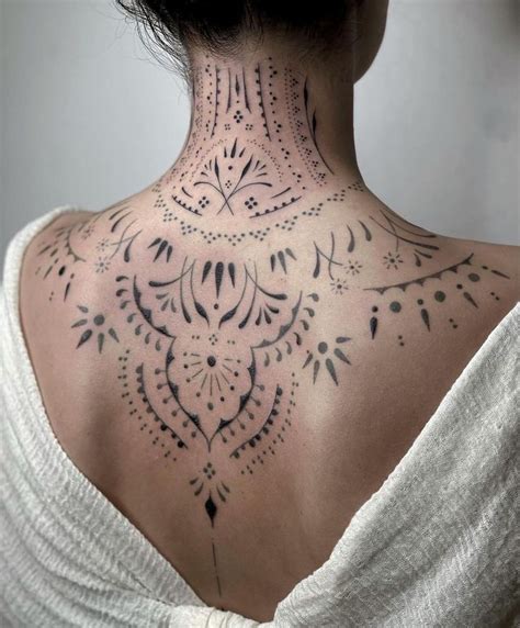 The Back Of A Woman S Neck Is Covered In Black And White Ink With Intricate Designs