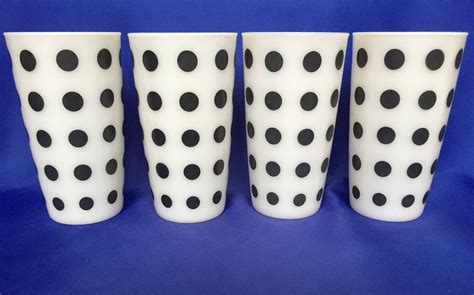 Four White And Black Polka Dot Cups Sitting Side By Side On A Blue