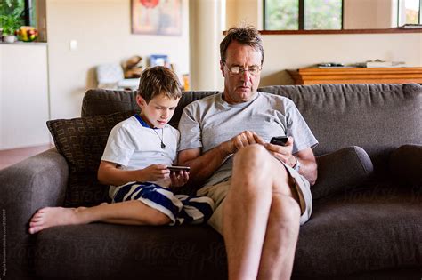 Grandfather And Grandson Sitting Together On Their Screens By Stocksy